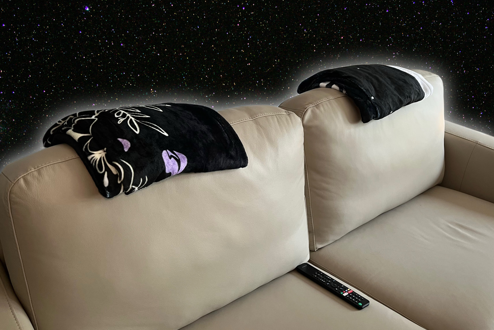 Fleece blankets draped over a beige couch against a starry night sky